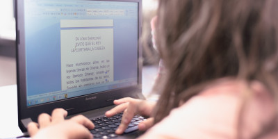 Una chica lee un texto desde una computadora