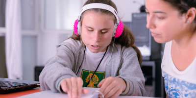 Una nena hace la tarea junto a su maestra