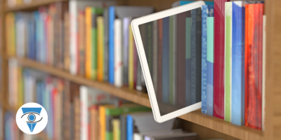 Foto de una tablet asomada en una biblioteca llena de libros.