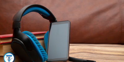 Un par de auriculares y un teléfono celular apoyados sobre varios libros.
