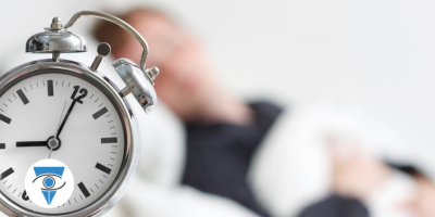 Imagen de un despertador y una persona durmiendo.