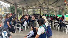 Foto de los asistentes al encuentro alrededor de mesas desayunando.